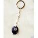 Deep purple natural Amethyst keychain with silver wire wrap, shown on white leather background 